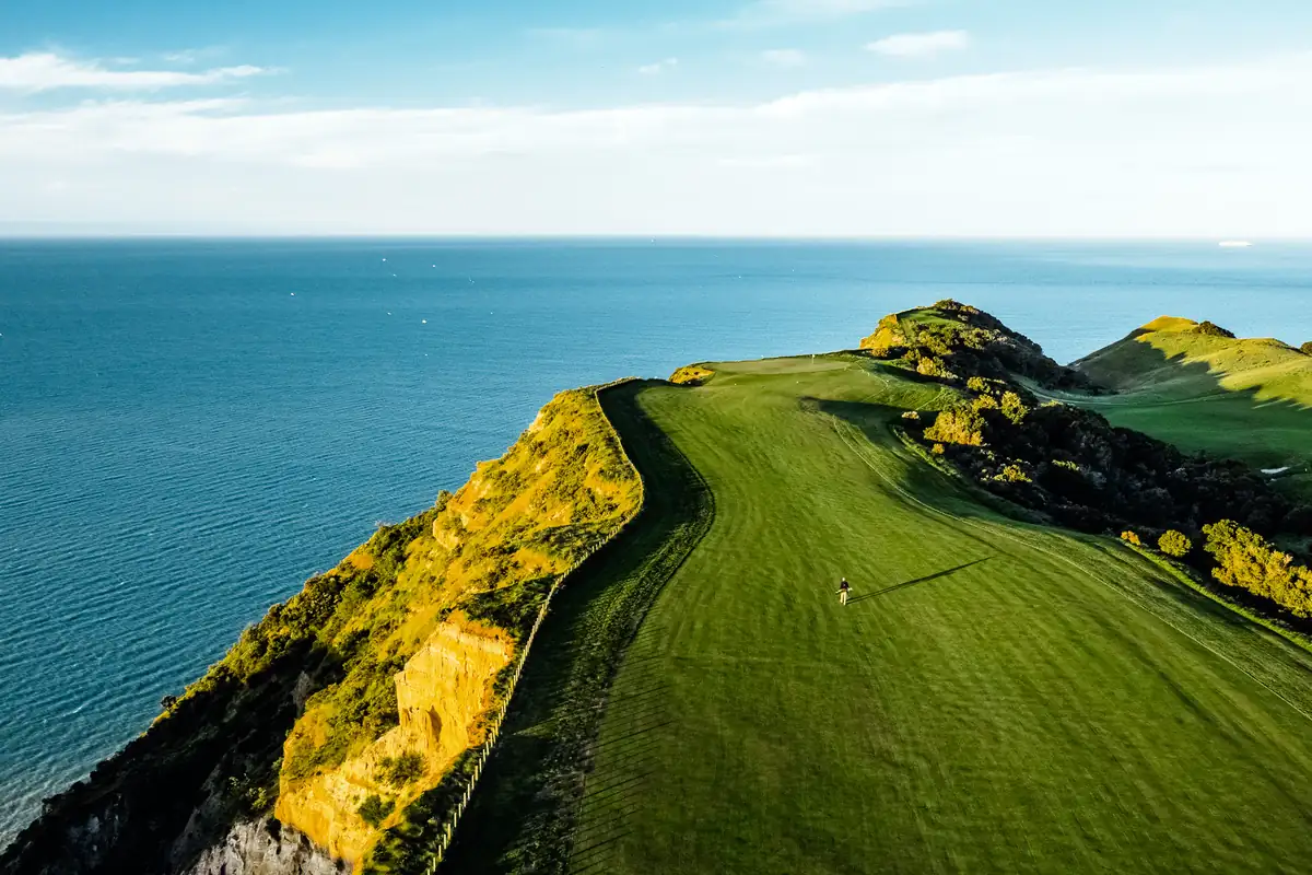 Aerial view of the clifftop golf course at Cape Kidnappers, Hawke's Bay, New Zealand, with dramatic golden cliffs dropping to the Pacific Ocean