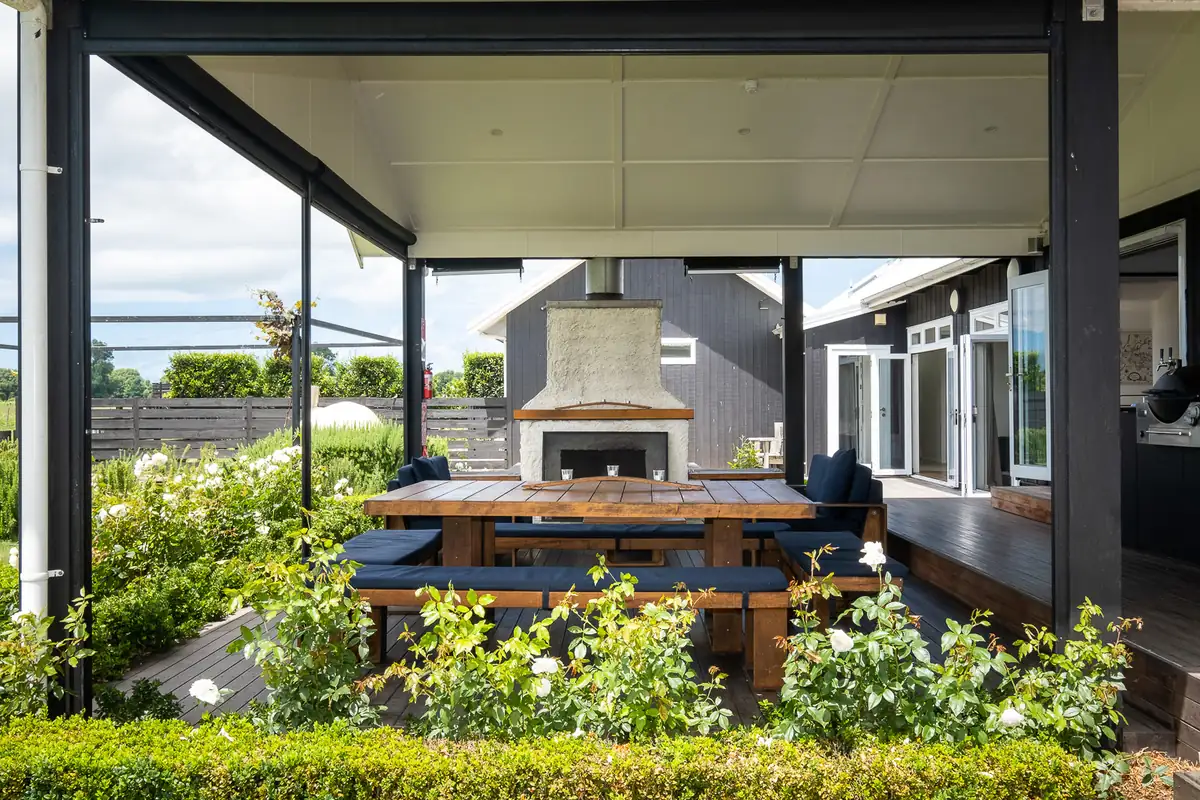 Covered outdoor dining area with fireplace and garden at Lawn Road Retreat, Hawke's Bay
