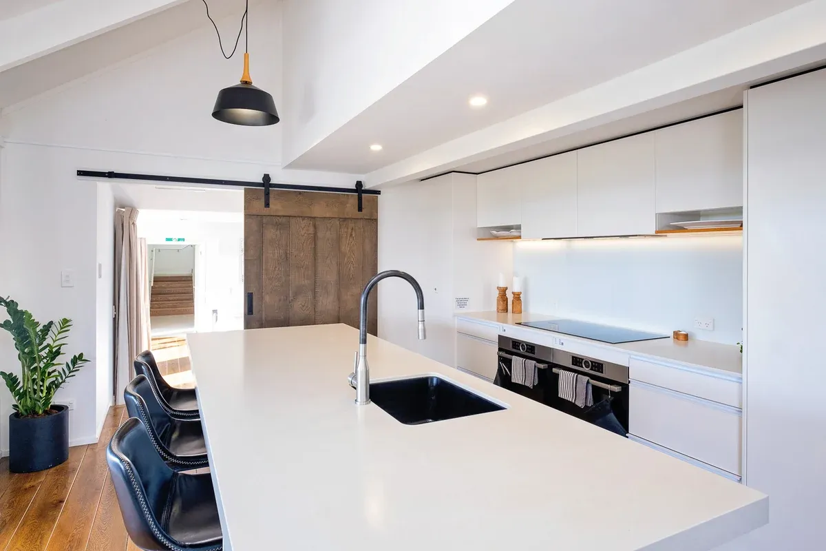 Main kitchen with island bench and barn door at Lawn Road Retreat, Hawke's Bay